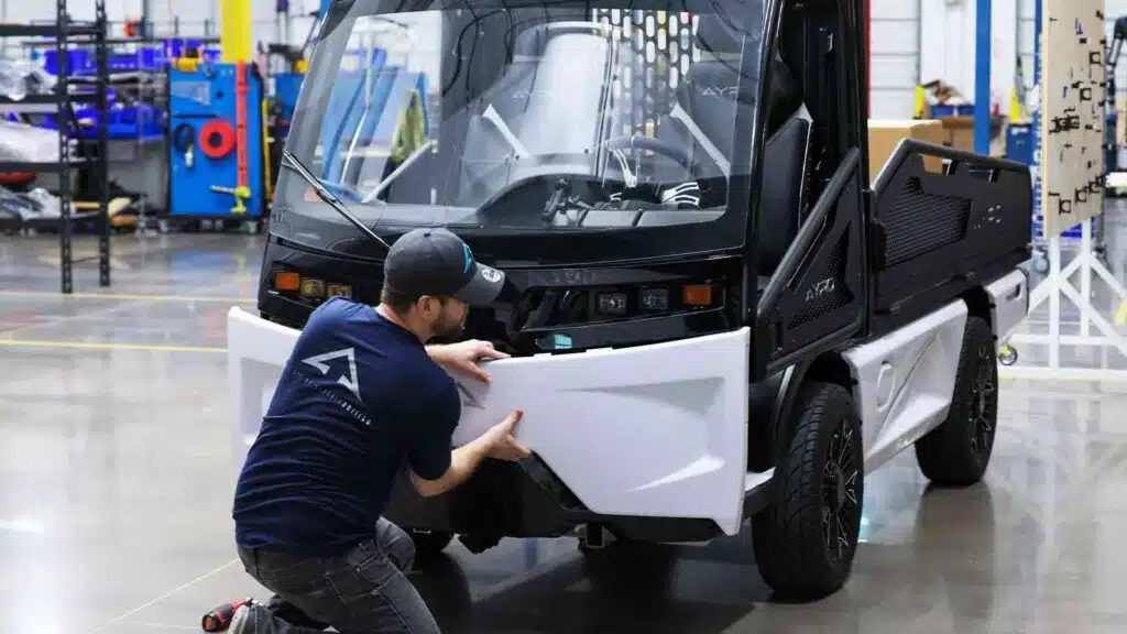 man adjusting front panel of AYRO Vanish low speed vehicle in factory