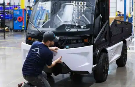 man adjusting front panel of AYRO Vanish low speed vehicle in factory